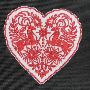 May include: A white heart-shaped patch with red embroidered reindeer and floral designs.