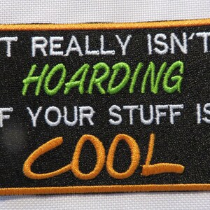 May include: Black embroidered patch with an orange border. The text reads "It really isn't hoarding if your stuff is cool".