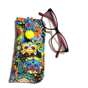 May include: A colorful eyeglasses case with a cat design and a pair of black-framed glasses with red arms. The case features a vibrant pattern of cats, flowers, and paisley shapes in various colors, including blue, yellow, and green.