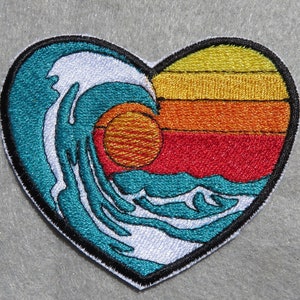 May include: A heart-shaped embroidered patch with a blue wave and a sunset in orange, red, and yellow colors.
