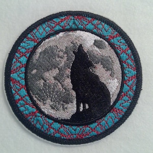 May include: Embroidered patch with a wolf howling at the moon. The moon is gray and white, and the wolf is black. The patch is surrounded by a turquoise and red border.