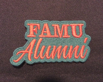 May include: A teal blue embroidered patch with the text "FAMU Alumni" in red lettering.