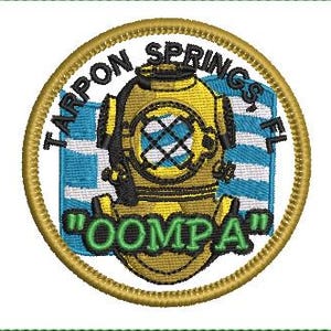 May include: Embroidered patch featuring a yellow diving helmet with black accents, set against a blue and white striped background. The patch is circular, with the words "Tarpon Springs, FL" and "OOMPA" in green text, all framed by a gold border.