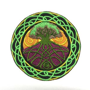 May include: Embroidered patch featuring a Celtic tree of life design. The patch has a circular shape with a black background and a green, yellow, and purple color scheme. The tree is green and brown, with intricate knotwork.
