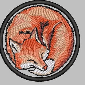 May include: A circular embroidered patch featuring a curled up orange fox sleeping inside a black circle.