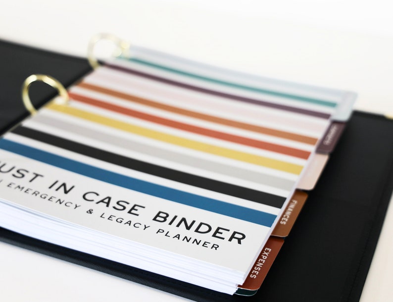 Pu&ograve; includere: Un raccoglitore nero con anelli dorati e divisori a linguette colorati etichettati "Spese", "Finanze" e "Just in Case Binder Emergency & Legacy Planner".
