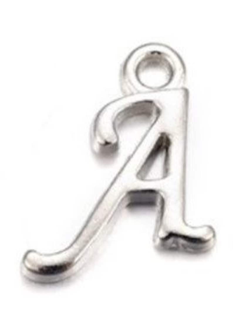 May include: Silver charm in the shape of the letter A. The letter is in a cursive style with a loop at the top for attaching to a chain or bracelet.
