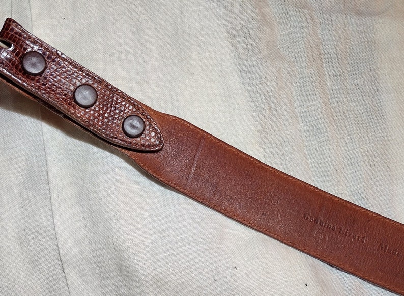 May include: Brown leather belt with a textured surface and three metal rivets. The belt is labeled "Genuine Lizard Skin Made in Italy."