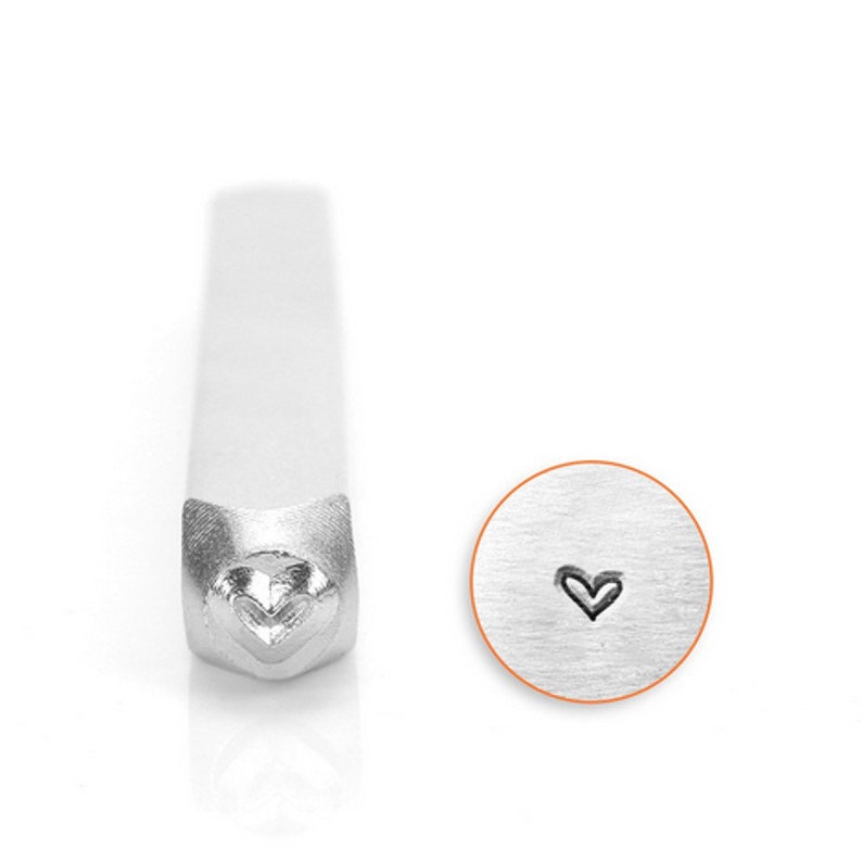 May include: A silver metal stamp with a heart design. The stamp is used to create impressions in metal.
