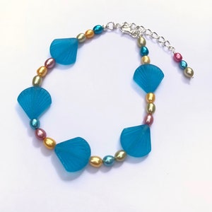 May include: A turquoise blue and multi-colored beaded bracelet with a silver clasp and blue shell charms.