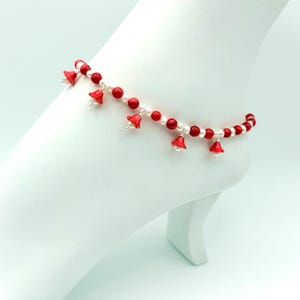 May include: Red and white beaded ankle bracelet with small red bell charms.