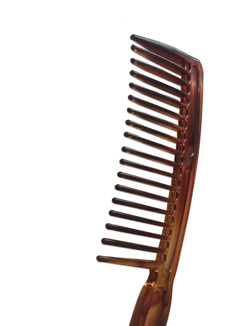 May include: A brown plastic comb with a wide handle and fine teeth.