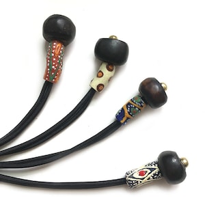 May include: Four black and brown wooden beads with colorful patterned glass beads attached to black elastic cord.