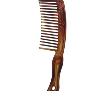 May include: A brown plastic comb with a curved handle. The comb has fine teeth and is designed for detangling hair.