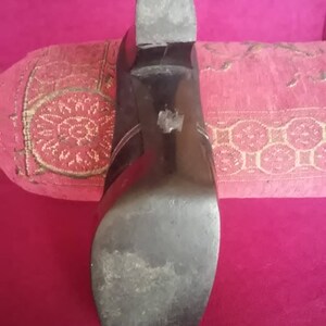 May include: Close-up of the bottom of a black leather heeled shoe. The sole is worn and has a slight scuff mark.