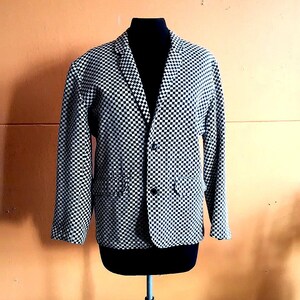 May include: A black and white checkered blazer with a button closure. The blazer is on a mannequin and has a classic style.