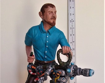 May include: A hand-painted figurine of a person holding a large, detailed, silver-colored, steampunk-style weapon with a blue and green barrel. The figurine is standing on a brown, textured base.