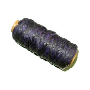 May include: A spool of dark purple waxed thread. The thread is tightly wound around a light brown wooden core. The texture of the thread appears woven, with visible strands. The spool is set against a white background.