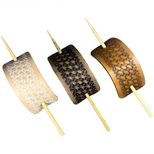 May include: Three leather hair barrettes in tan, brown, and light brown, each with a unique woven pattern and a wooden stick. The barrettes have a curved shape and are designed to hold hair in place. The barrettes are a hair accessory.