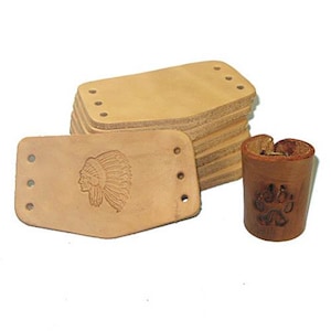 May include: A stack of light brown leather pieces with pre-drilled holes, alongside a single piece with an embossed Native American profile. A small, cylindrical leather piece with a paw print design is also present.