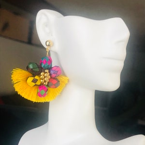 May include: A pair of yellow tassel earrings with colorful woven beads and gold accents.
