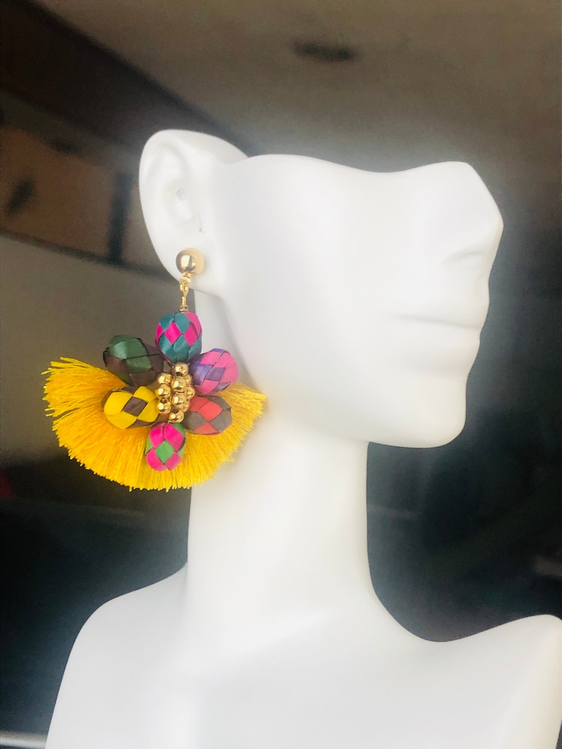 May include: A pair of yellow tassel earrings with colorful woven beads and gold accents.