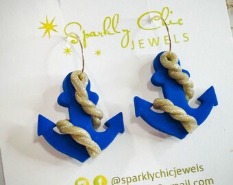 May include: A pair of blue anchor earrings with gold rope accents. The earrings are made of polymer clay and have a hoop style closure. The earrings are handmade and are perfect for nautical themed outfits.
