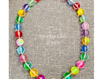 May include: A rainbow colored beaded necklace with a gold clasp. The beads are iridescent and have a frosted finish.