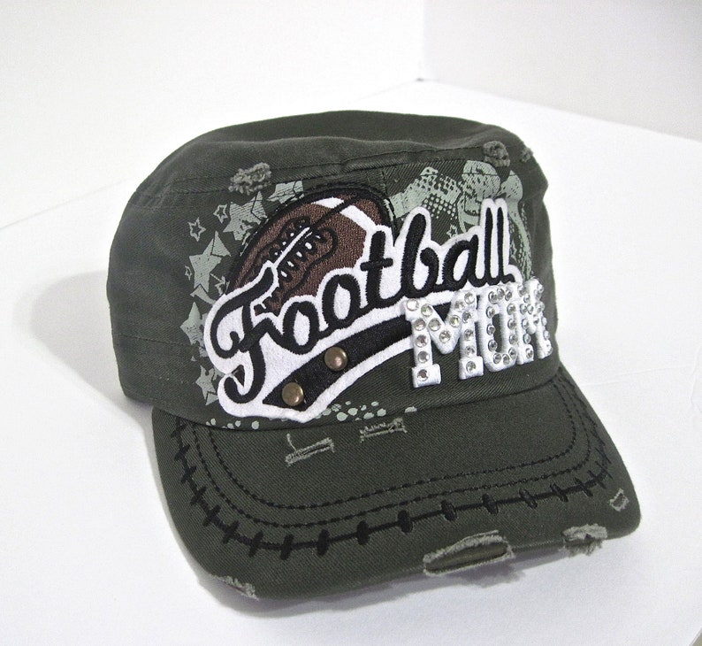 May include: A green camouflage baseball cap with a white and black "Football Mom" patch with rhinestones. The patch features a football graphic.