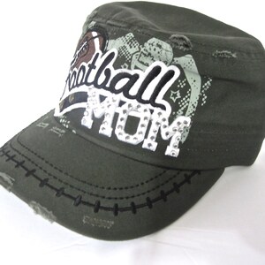 May include: A green camouflage baseball cap with a distressed look. The cap has a white patch with the text "Football Mom" in black and white lettering with rhinestones.