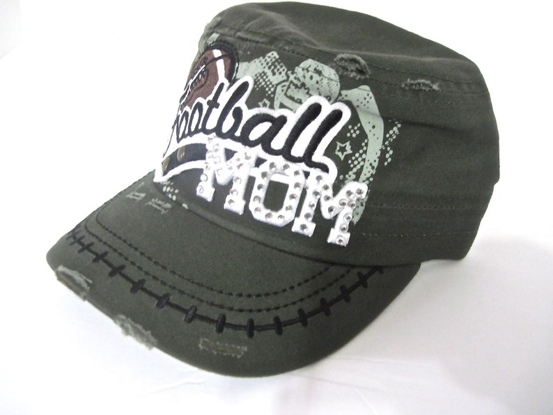 May include: A green camouflage baseball cap with a distressed look. The cap has a white patch with the text "Football Mom" in black and white lettering with rhinestones.