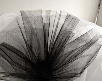 Peut inclure: Tulle noir, un tissu fin et délicat, est rassemblé et déployé en éventail dans une forme circulaire. Le tissu est doux et fluide, avec une texture en maille fine.