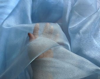 May include: A light blue sheer fabric with a soft, flowing texture. The fabric is translucent and has a subtle shimmer.