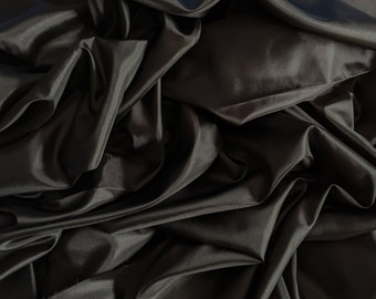 May include: Black Habotai fabric, a smooth, silky material with a luxurious drape. The fabric is folded and arranged in a way that shows its texture and sheen.