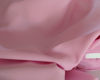 May include: A close-up of a soft, pink fabric folded in a smooth, flowing drape. The fabric is smooth and has a subtle sheen.