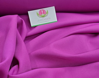 May include: A close-up of a vibrant magenta fabric, showing its smooth texture and soft drape. The fabric is folded and arranged in a way that highlights its color and texture. The text "JustDetails" is visible on a white tag.
