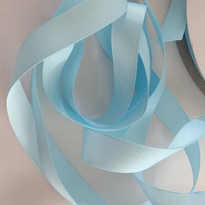 May include: A close-up of a light blue satin ribbon. The ribbon is folded and twisted, showing its texture and sheen.