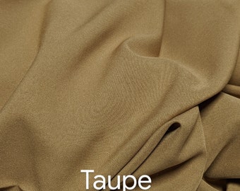 Puede incluir: Primer plano de una tela lisa de color topo. La tela está doblada y tiene un tacto suave y lujoso.