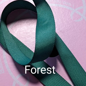 May include: A close-up of a forest green ribbon. The ribbon is folded in a loop and the word "Forest" is printed in white below the ribbon.