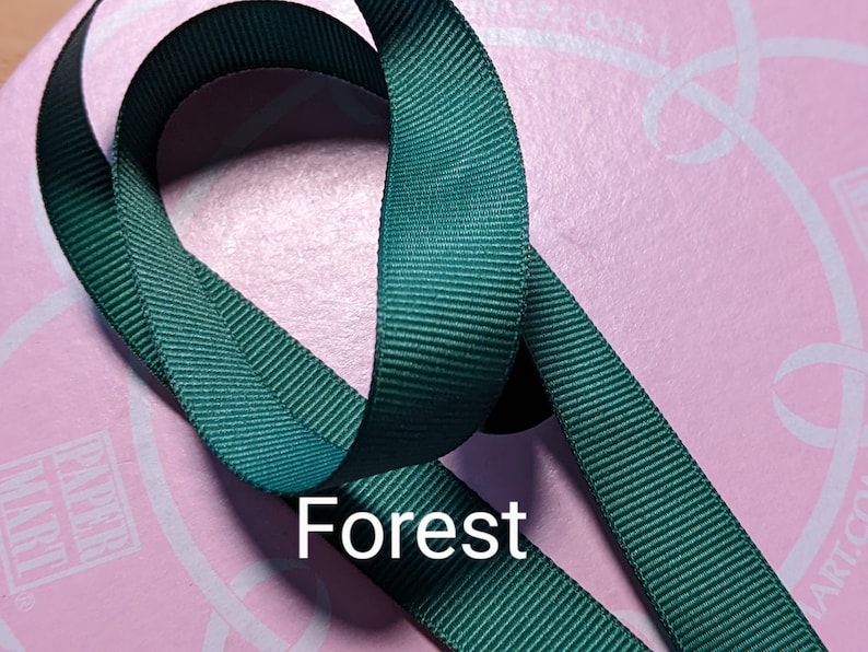 May include: A close-up of a forest green ribbon. The ribbon is folded in a loop and the word "Forest" is printed in white below the ribbon.