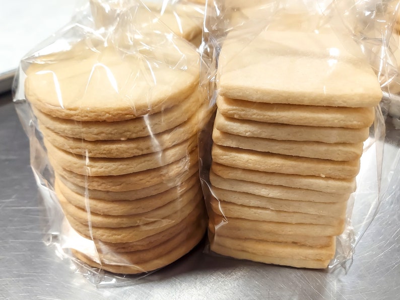 May include: Two bags of plain cookies, one with round cookies stacked on top of each other, and the other with rectangular cookies stacked on top of each other.