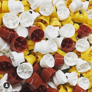 May include: A collection of spray paint caps in white, yellow, and brown. The caps have different designs and are arranged in a random pattern.