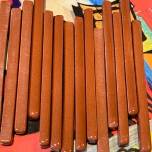 May include: A set of 15 brown wooden dowels arranged in a heart shape. The dowels are smooth and have a slightly glossy finish.