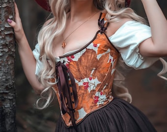 May include: A woman with long blonde hair wearing a red witch hat and a brown and orange corset with a floral pattern. She is standing in a forest and holding a tree trunk.