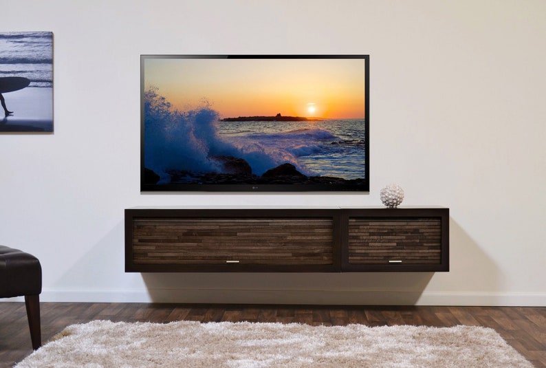 May include: A contemporary TV unit with a dark wood finish, featuring two drawers and a large flat-screen TV showing a sunset over the sea. A decorative orb sits on top of the cabinet.