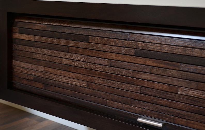 May include: A dark brown wooden cabinet door with a horizontal plank design. The door is framed in a darker wood and features a silver handle. The wood grain is visible, adding texture.