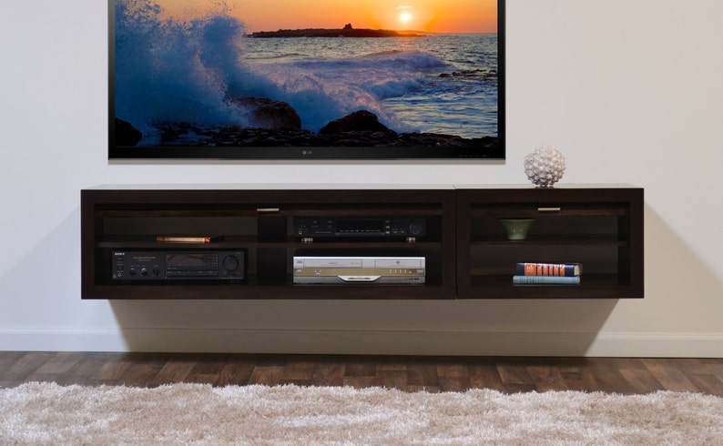 May include: A dark brown, wall-mounted entertainment unit with several compartments. It has a TV above and a DVD player, receiver, and other media components inside. A decorative sphere sits on top.