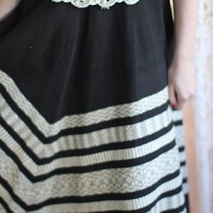 May include: A black skirt with a white and gray embroidered pattern. The skirt has a lace waistband.
