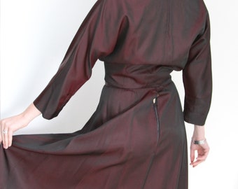 May include: A burgundy dress with a black velvet collar and a back zipper. The dress has a fitted bodice and a full skirt.