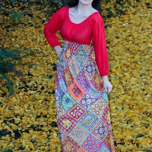 K&ouml;nnte beinhalten: Eine Frau tr&auml;gt ein rot-wei&szlig;es Maxikleid mit einem roten Oberteil und einem langen Rock. Sie steht auf einem Feld mit gelben Bl&auml;ttern.